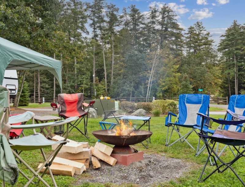 Camp fire burning with chairs set around it.